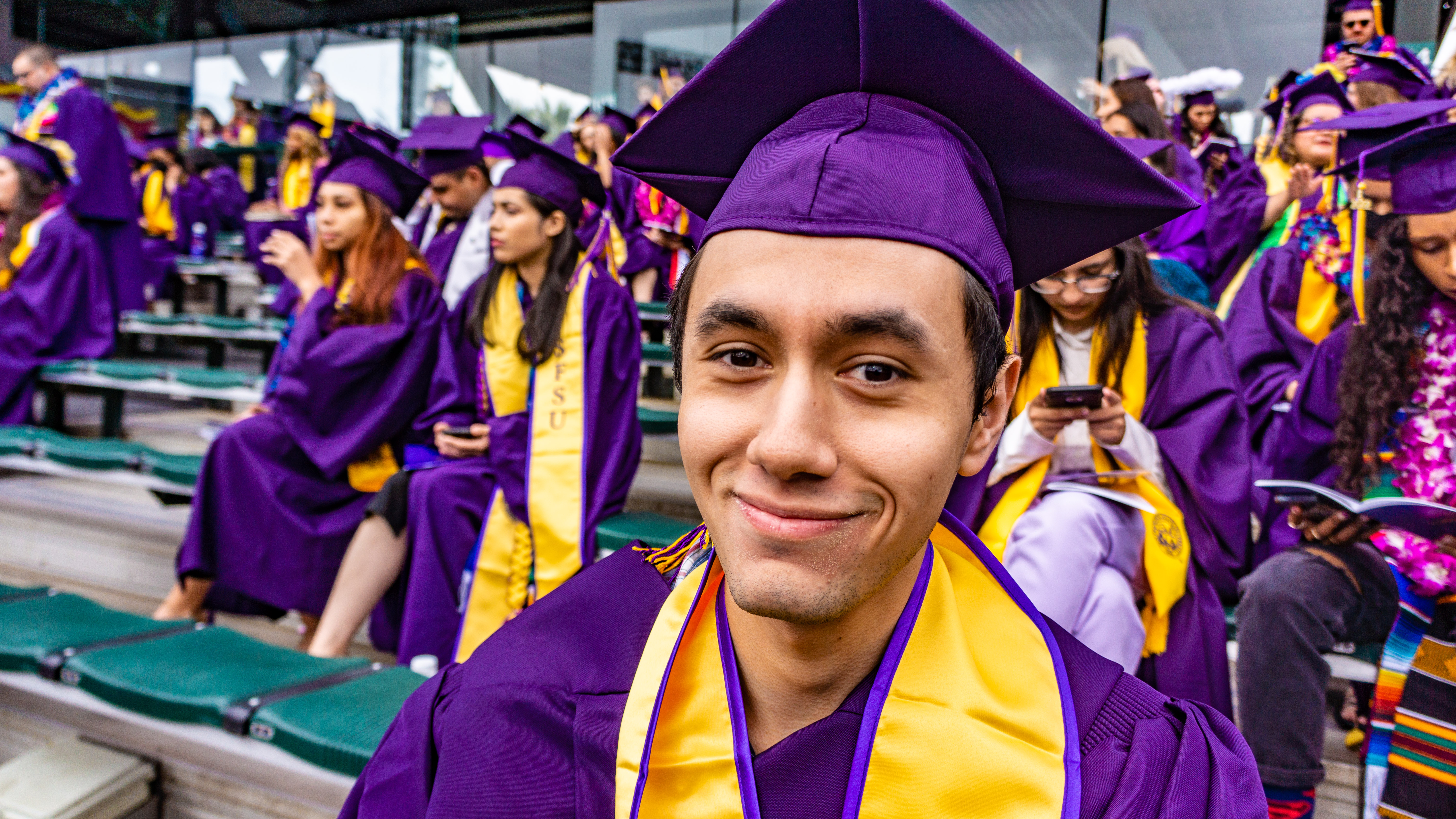 a student smiling close up with their graduation attire on